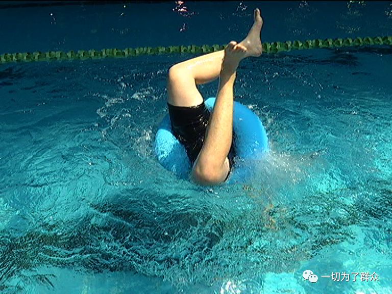 一个孩子戴着游泳圈在泳池中玩耍,没想到却突然翻倒,四脚朝天倒立在水